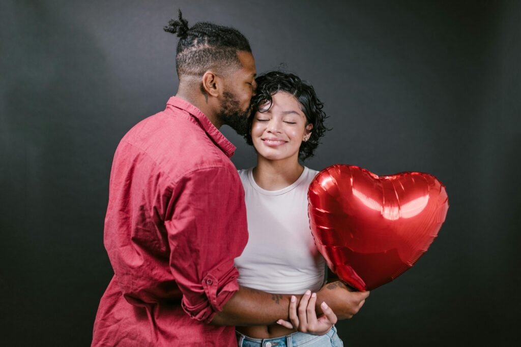 A loving couple embraces while holding a heart-shaped balloon, celebrating romance.
