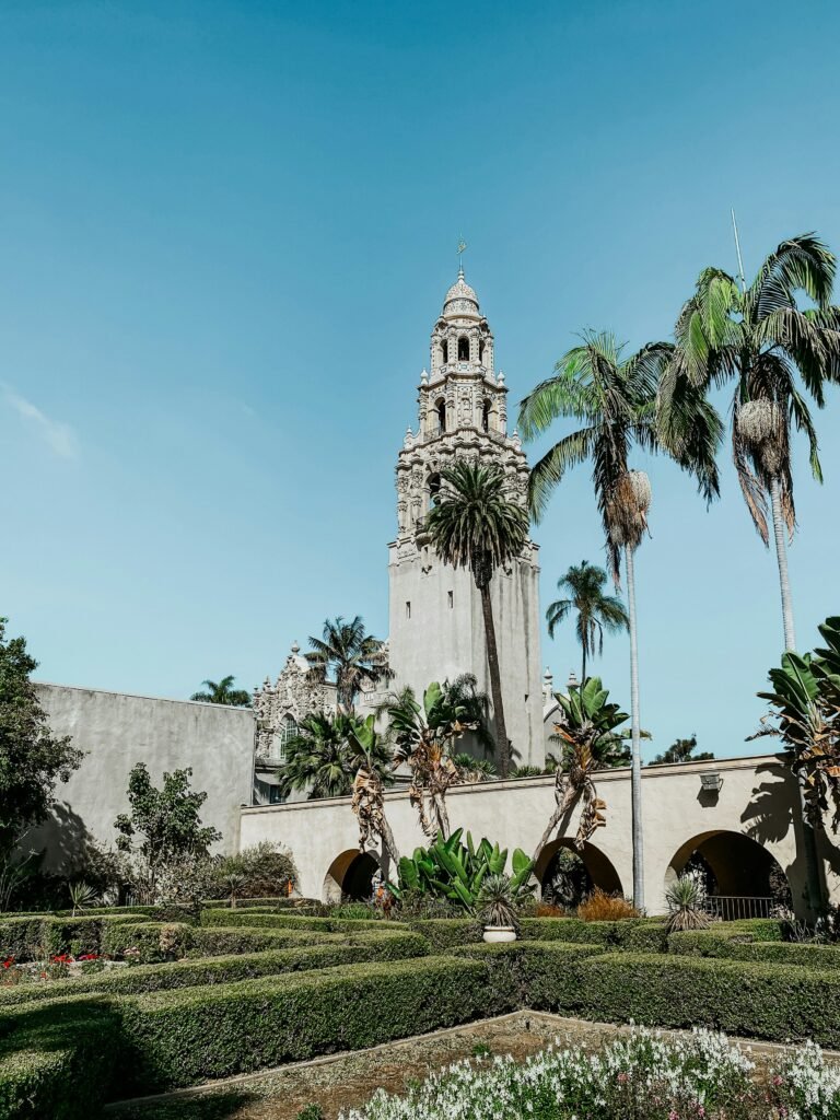a large building with a clock tower in the middle of a garden Balboa Park San Diego