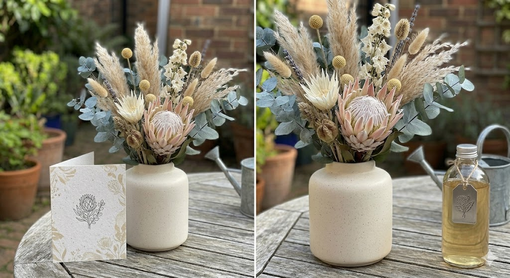 A close-up of a high-quality, modern dried flower arrangement featuring eucalyptus, pampas grass, and preserved protea in a minimalist ceramic vase. Beside it sits a hand-written card with a heartfelt Mother's Day quote.